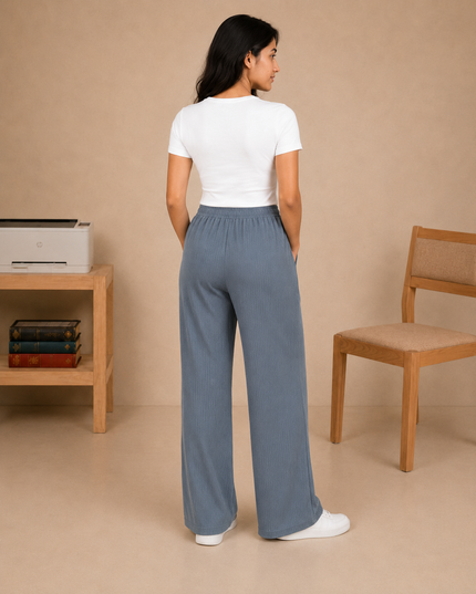 Woman wearing a white t-shirt and blue pants standing in a room with a printer and chair.