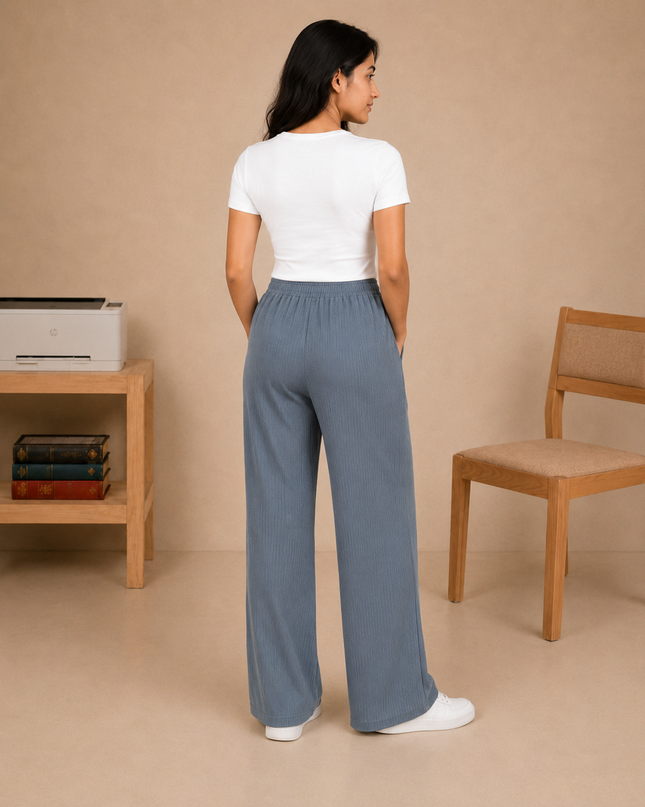 Woman wearing a white t-shirt and blue pants standing in a room with a printer and chair.